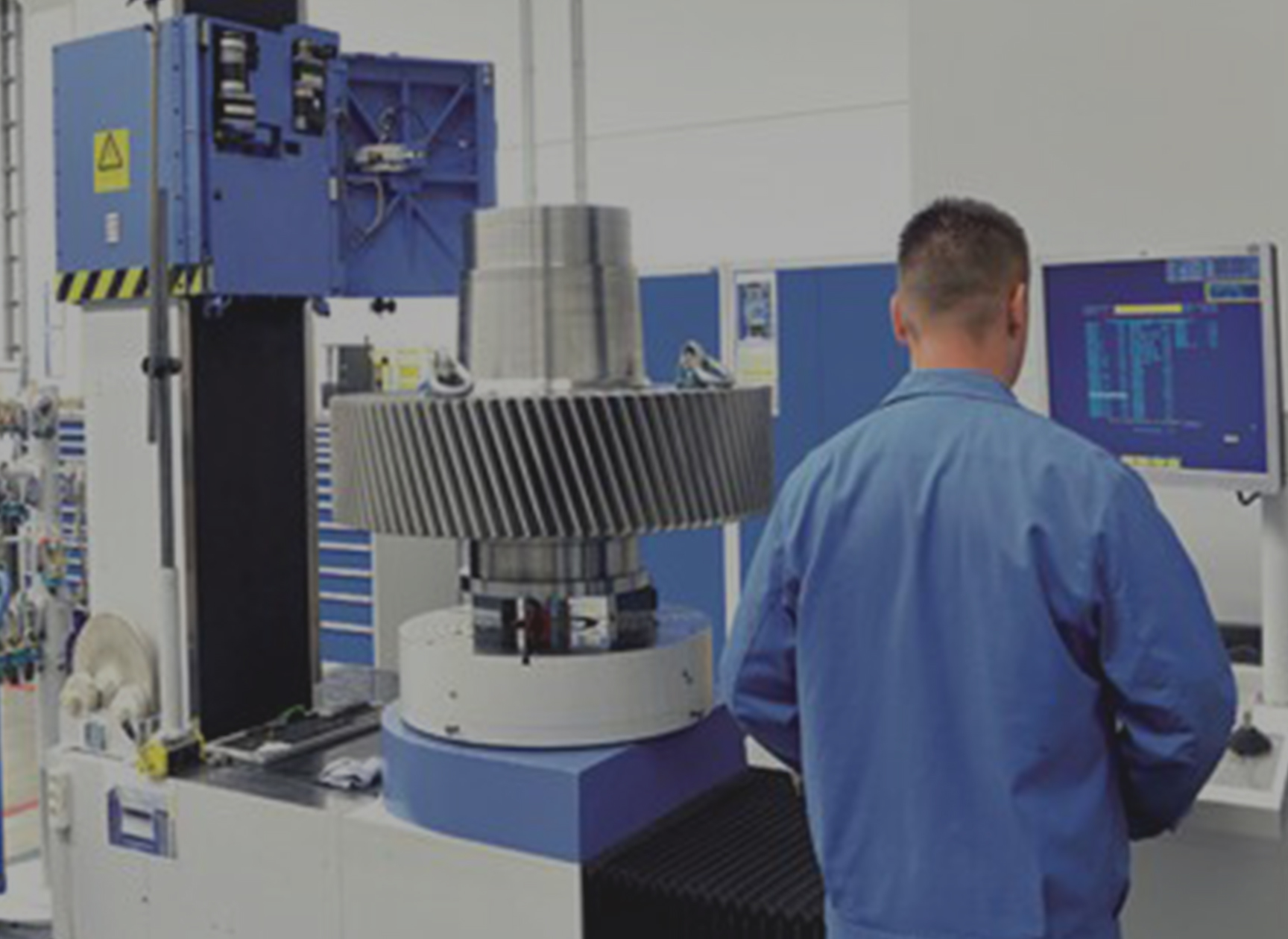 ehb-electronics Loesungen Maschinenbau Anlagenbau A man in workwear standing in front of an industrial unit, operating a control panel.